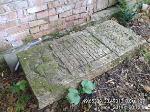 The only tombstone from destroyed cemetery lies near the private barn, 2019
