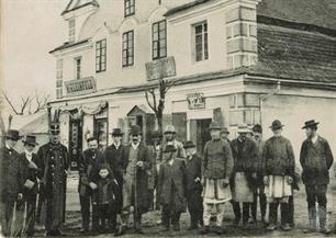 Jews and other people in front of the shops. Above the entrance to the left is a Jewish name - M.Klienfeld Jews and other people in front of the shops. Above the entrance to the left is a Jewish name - M.Klienfeld